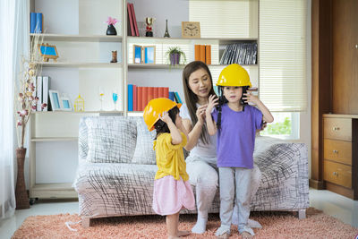 A beloved asian mother and daughter pretend to be an engineer and smile with a yellow helmet 