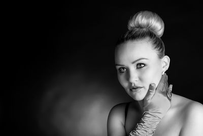 Portrait of young woman against black background