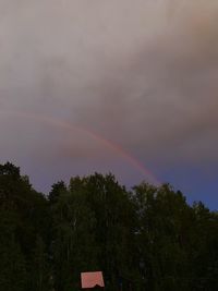 Low angle view of rainbow over trees against sky