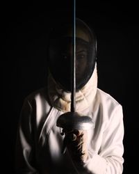 Portrait of man wearing mask against black background
