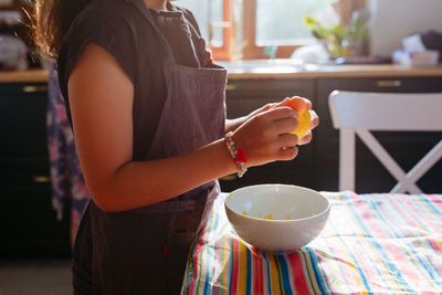 Standing girl in apron grating lemon preparing cake in the kitchen at home