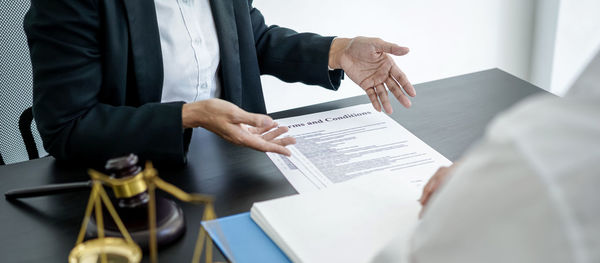 Midsection of business colleagues shaking hands in office