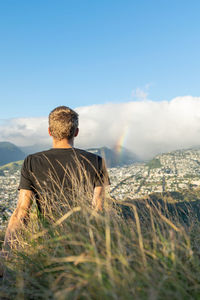 Rear view of man looking at rainbow against sky