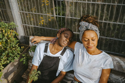 Female volunteers with eyes closed relaxing at community garden