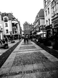 People walking on footpath amidst buildings in city