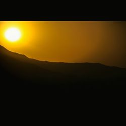 Scenic view of silhouette landscape against orange sky