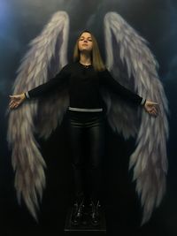 Young woman standing against angel wings