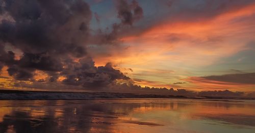 Scenic view of sea against dramatic sky during sunset