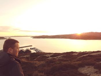 Man looking at sea against sky during sunset