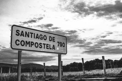 Information sign by road against sky