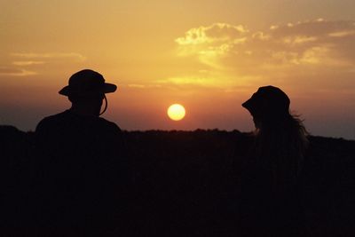 Silhouette people against orange sky during sunset