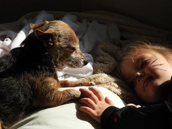 Close-up of cute girl lying on bed with dog