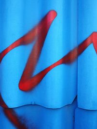 Red graffiti on blue corrugated iron