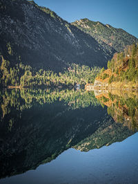 Reflecting mirror lake in austria with a little house