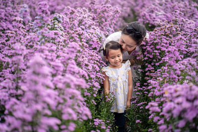 Woman standing by purple flowering plants