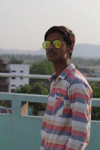 Young man standing against retaining wall on building terrace