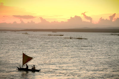 Silhouette man in sea against sky during sunset