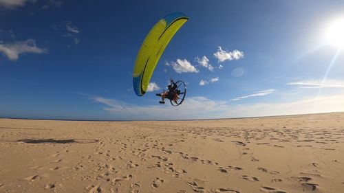 Person paramotoring against sand and sky