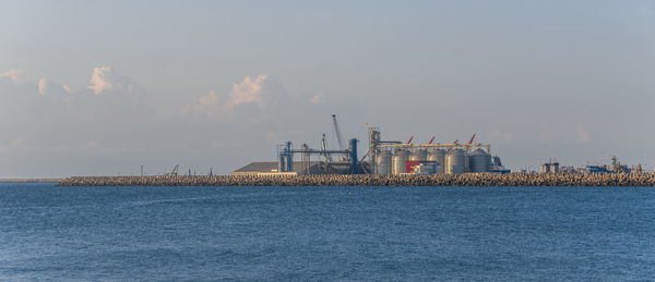 Factory by sea against sky