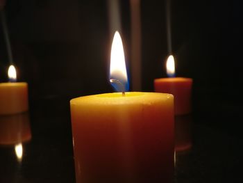 Close-up of lit candles in darkroom