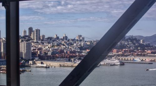 City at waterfront against cloudy sky