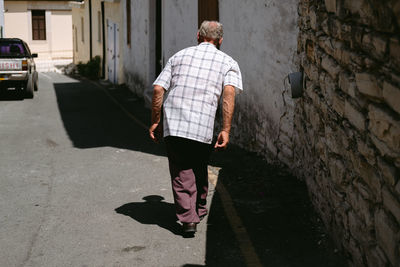 Rear view of man walking on street in city