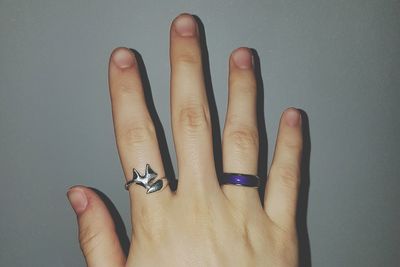 Cropped hand wearing rings by gray wall
