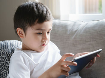 Boy looking at camera while sitting on sofa at home