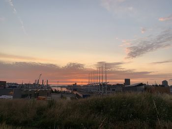 Factory on field against sky during sunset