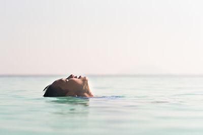 Person swimming in sea against clear sky