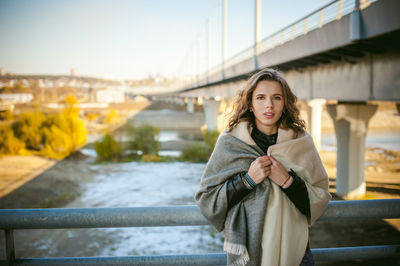 Portrait of young woman with shawl standing on bridge