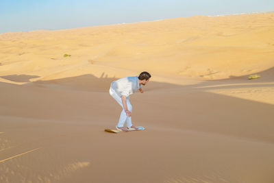 Rear view of man walking on sand at desert