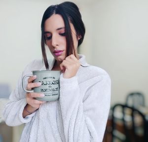 Portrait of a beautiful young woman standing against wall