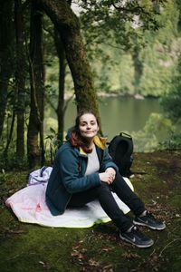Portrait of smiling young woman sitting in forest