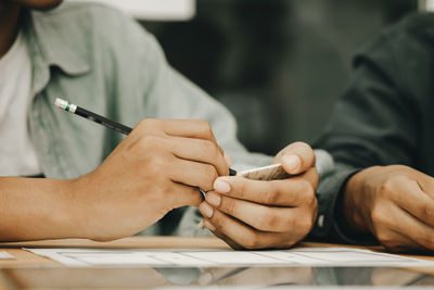 Close-up of man holding hands on table