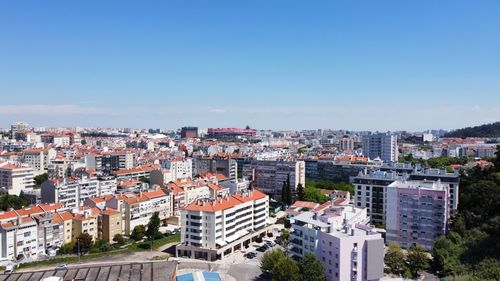 High angle view of buildings in city against clear blue sky
