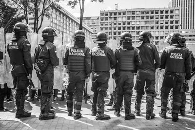Rear view of police force standing in city