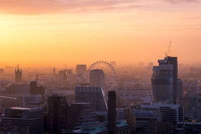 Modern buildings in city against sky during sunset