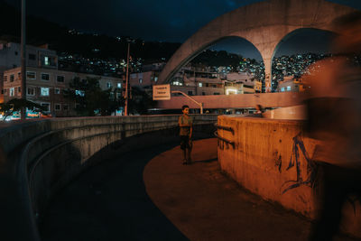 People on illuminated bridge at night