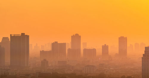 Air pollution. smog and fine dust of pm2.5 covered city in the morning with orange sunrise sky. 