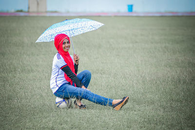 Low section of woman with umbrella on field