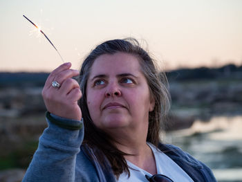 Portrait of woman holding water against sky