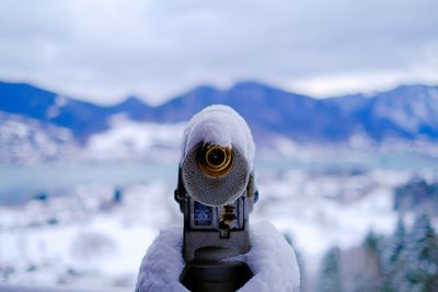 Close-up of snow capped binocular against mountain silhouette 