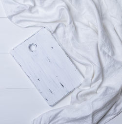Directly above shot of white wooden cutting board with fabric on table