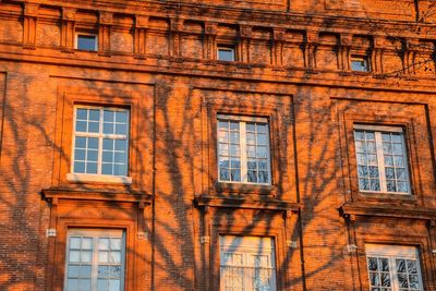 Low angle view of old building with tree reflection at sunset