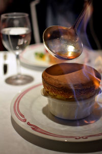 Spoon pouring caramel on flammable dessert souffle served on table