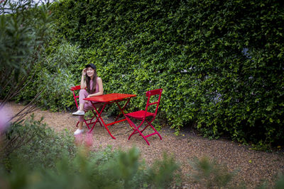 Portrait of smiling woman sitting on chair against plants