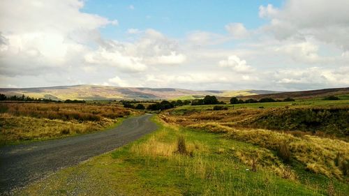 Road amidst field against sky