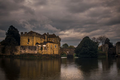 Old building by lake against sky