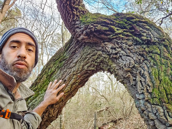Portrait of young man against tree trunk